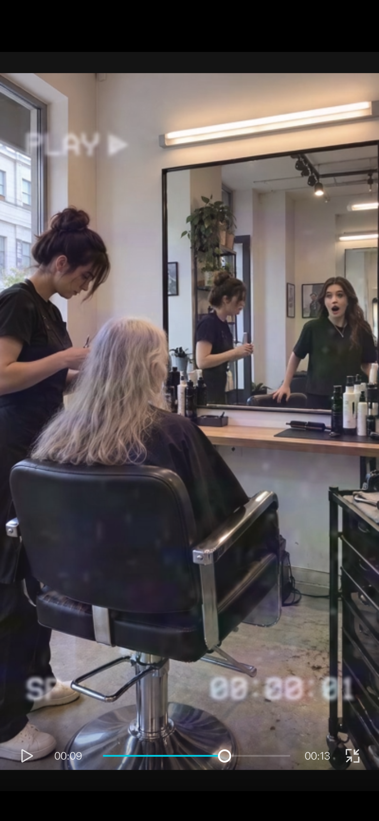 Older-looking client seated while younger-looking woman stands in the mirror